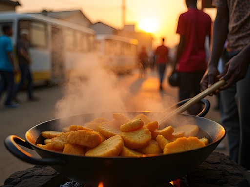 Kelewele street food vendor frying spiced plantains at sunset in Kumasi